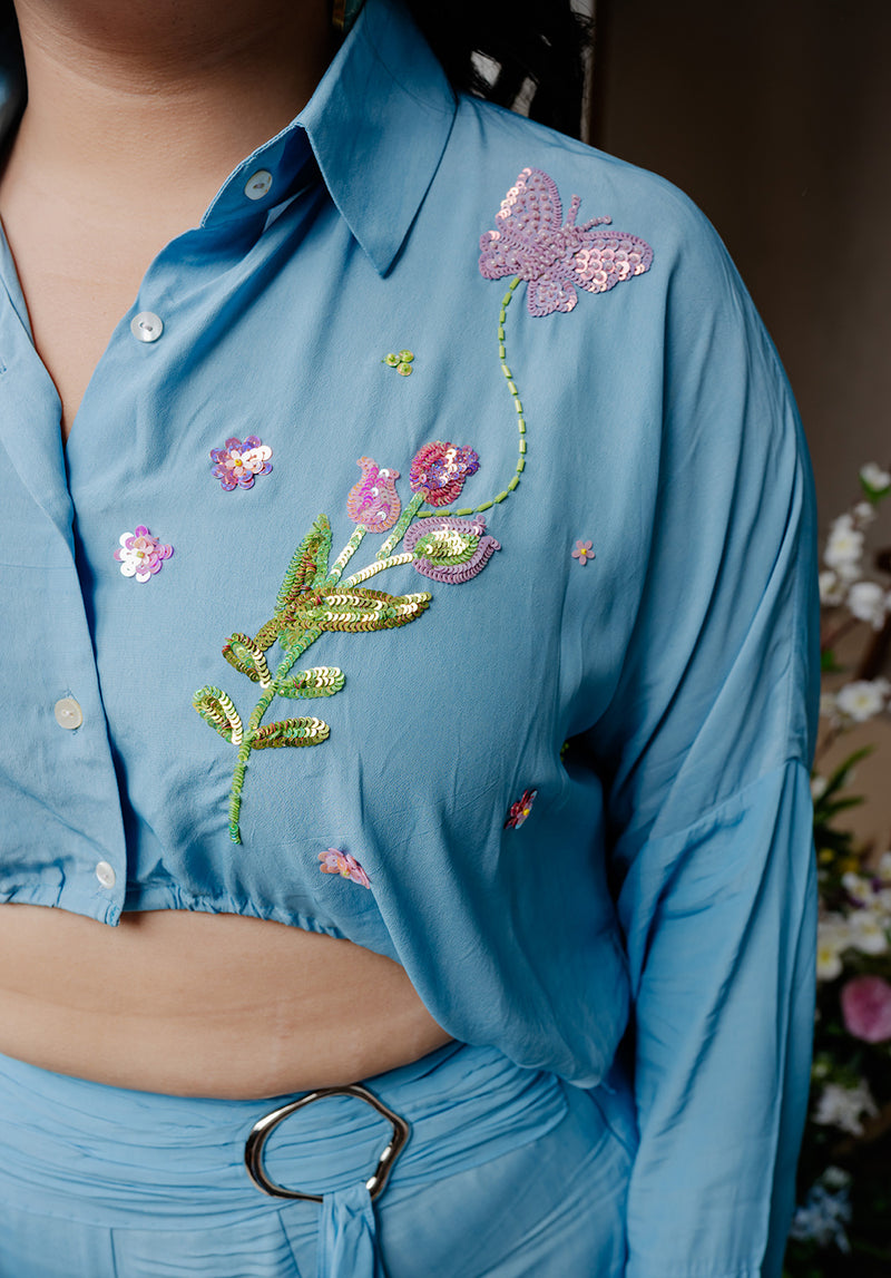 Detailed close-up of the floral hand embroidery on the cropped shirt, highlighting intricate craftsmanship and delicate stitching on soft crepe fabric.