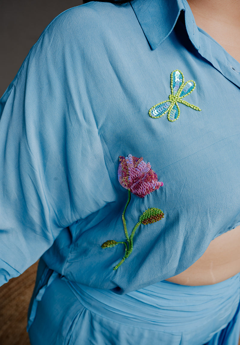 Detailed close-up of the floral hand embroidery on the cropped shirt, highlighting intricate craftsmanship and delicate stitching on soft crepe fabric.